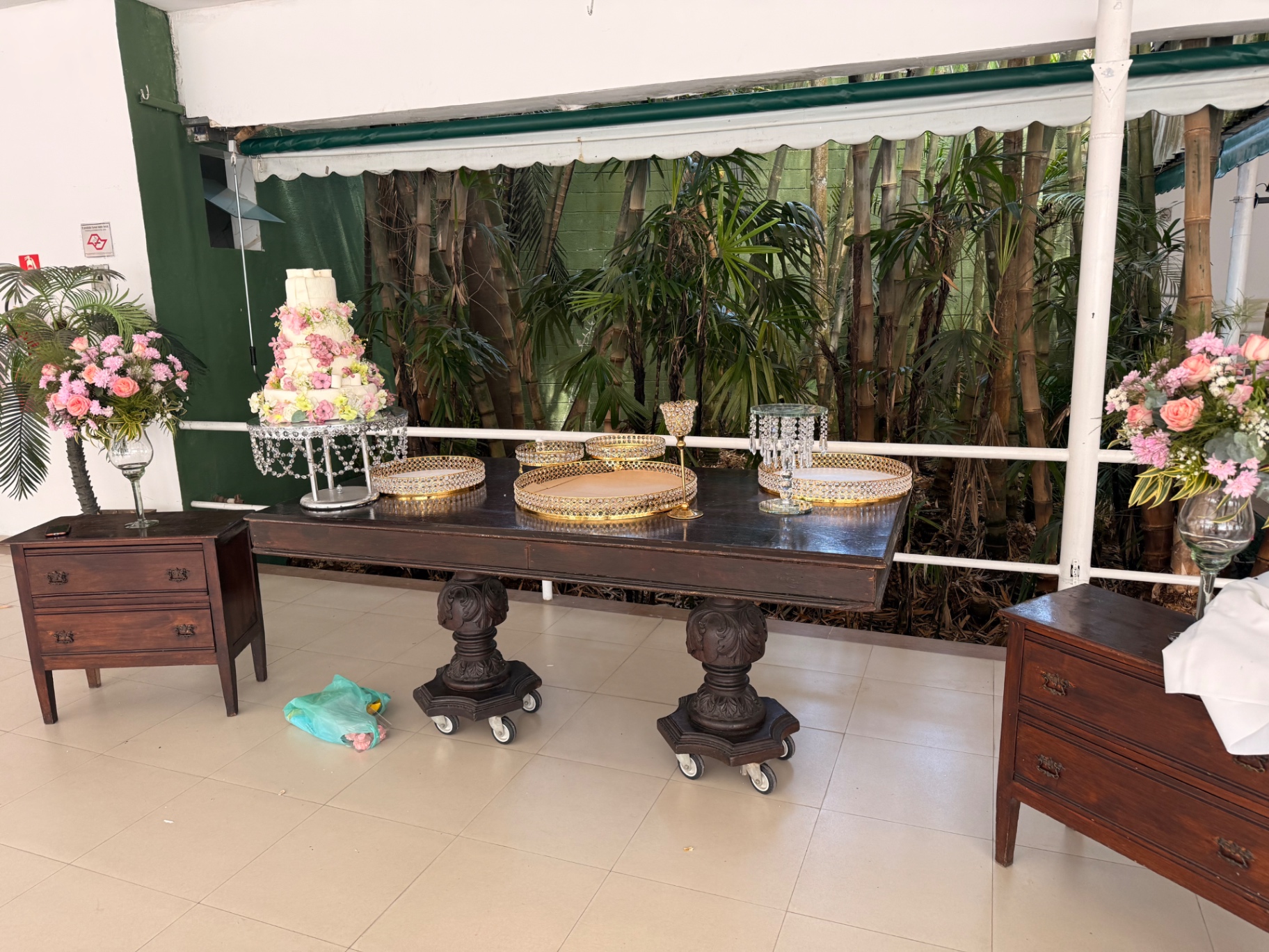Mesa de doces com flores rosas e bandejas douradas